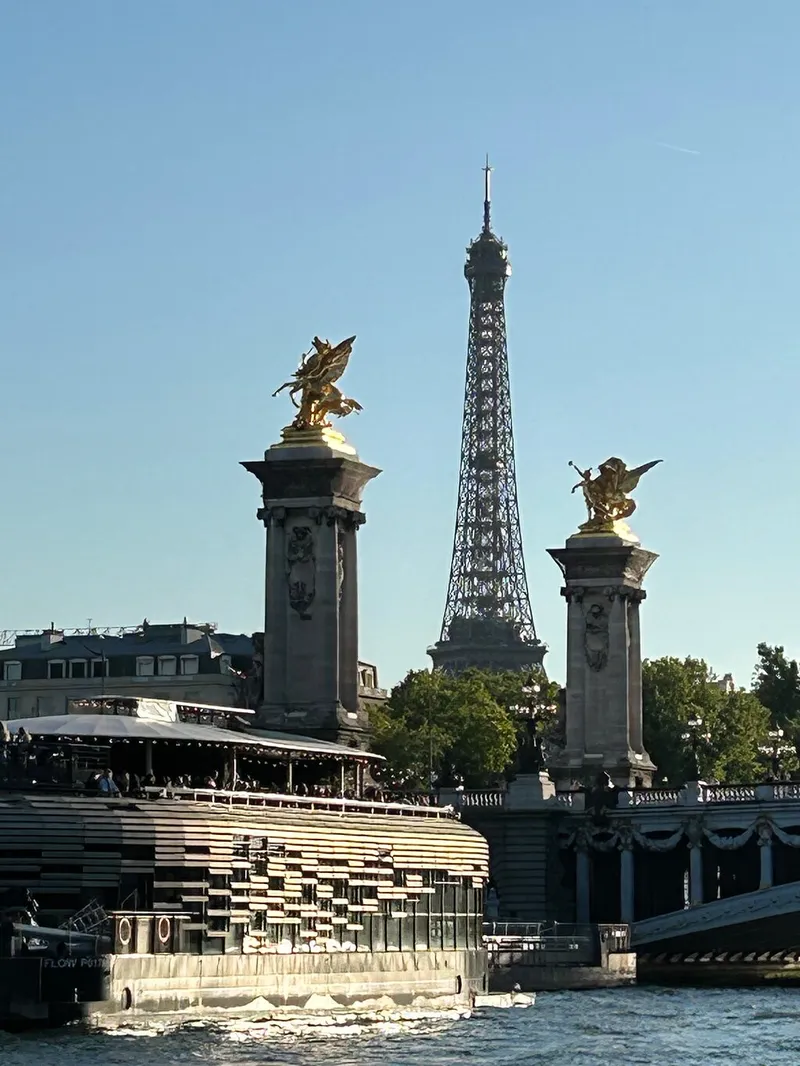 Die vergoldeten Statuen der Pont Alexandre III mit dem Eiffelturm dazwischen, vom Fluss aus gesehen