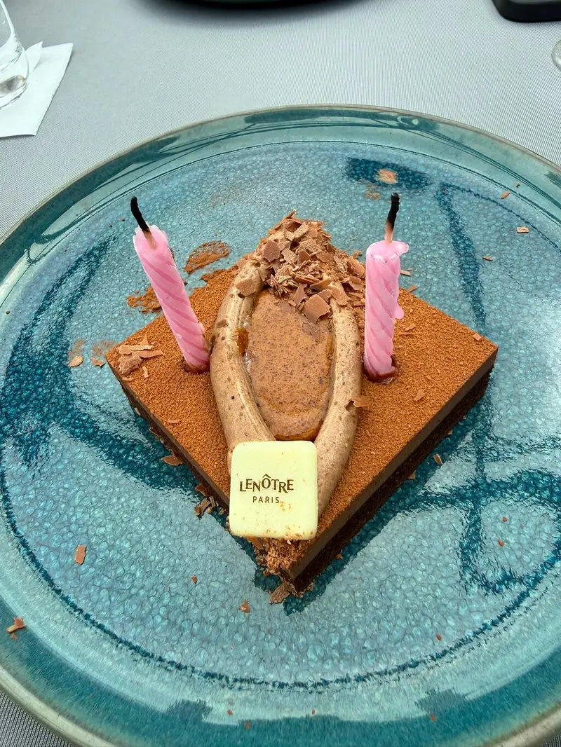 Ein Schokoladendessert mit zwei rosa Geburtstagskerzen und einer Platte aus weißer Schokolade