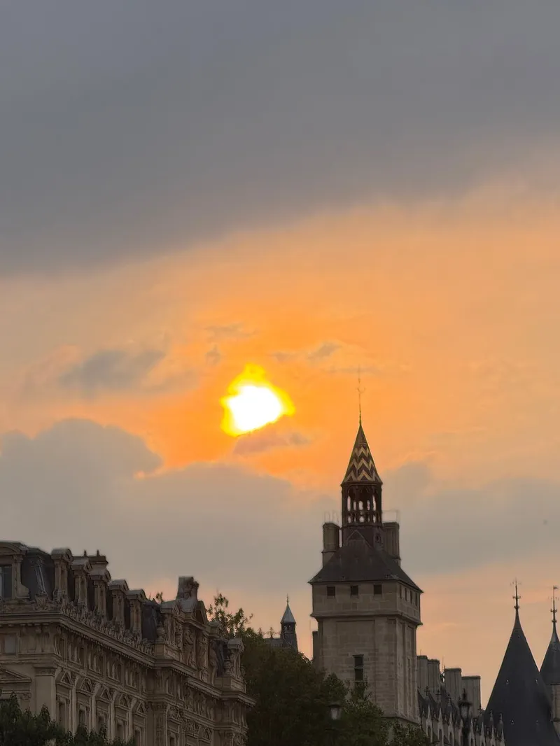 Die Sonne geht hinter den Dächern von Paris und einer Kuppel unter, gesehen von der Seine